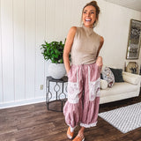 Soft, lightweight cotton pants that blend rose and grey plaid with creamy floral patchwork, lacey cream crochet trim, and a patchwork-trimmed ruffled hemline. Elastic drawstring waist and wide-leg silhouette with lace at the cuffs.
