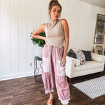 Soft, lightweight cotton pants that blend rose and grey plaid with creamy floral patchwork, lacey cream crochet trim, and a patchwork-trimmed ruffled hemline. Elastic drawstring waist and wide-leg silhouette with lace at the cuffs.