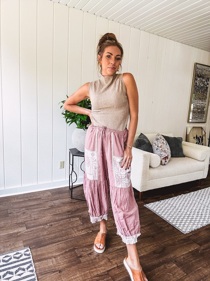 Soft, lightweight cotton pants that blend rose and grey plaid with creamy floral patchwork, lacey cream crochet trim, and a patchwork-trimmed ruffled hemline. Elastic drawstring waist and wide-leg silhouette with lace at the cuffs.