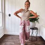 Soft, lightweight cotton pants that blend rose and grey plaid with creamy floral patchwork, lacey cream crochet trim, and a patchwork-trimmed ruffled hemline. Elastic drawstring waist and wide-leg silhouette with lace at the cuffs.