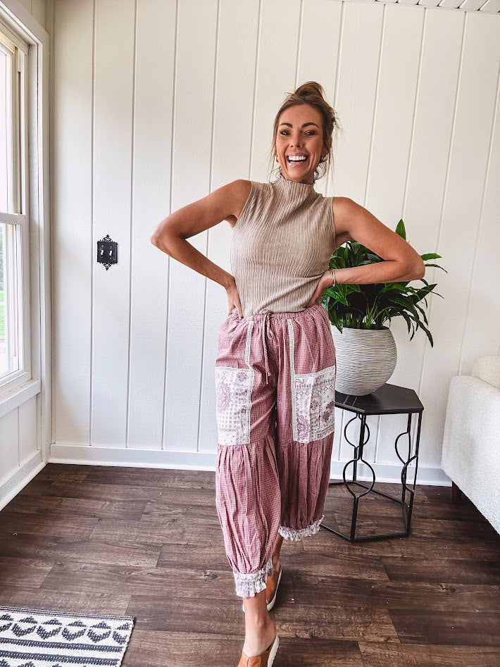 Soft, lightweight cotton pants that blend rose and grey plaid with creamy floral patchwork, lacey cream crochet trim, and a patchwork-trimmed ruffled hemline. Elastic drawstring waist and wide-leg silhouette with lace at the cuffs.