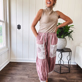 Soft, lightweight cotton pants that blend rose and grey plaid with creamy floral patchwork, lacey cream crochet trim, and a patchwork-trimmed ruffled hemline. Elastic drawstring waist and wide-leg silhouette with lace at the cuffs.