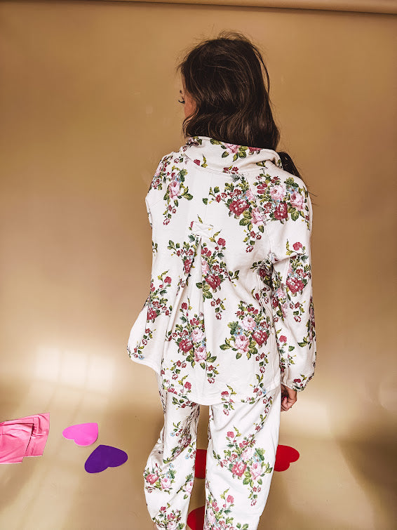 Ivory lounge set with pink, blue, and green florals, a quarter-zip top with kangaroo pocket, mock neck, and hi-low hem and matching bottoms with drawstring waist and pockets.