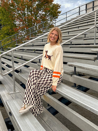Cream lightweight long sleeved sweater with Weiner Dog graphic on front with orange stripes at the sleeves.
