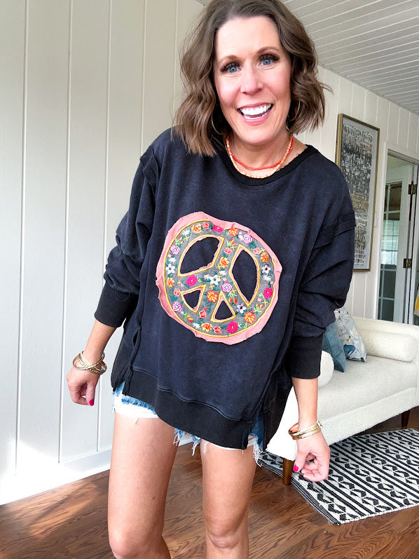 Washed charcoal pullover with exposed seams, a coral and floral peace patch on the front and split front hem.