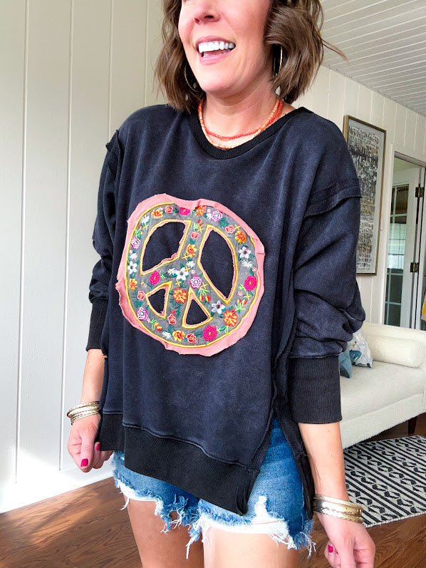 Washed charcoal pullover with exposed seams, a coral and floral peace patch on the front and split front hem.
