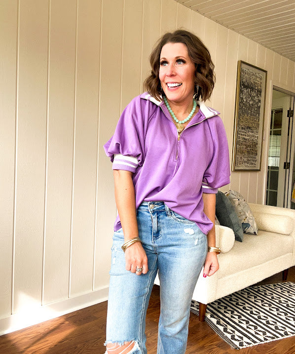 Soft, orchid 1/4 zip top with short sleeves and white striped trim at the collar and elastic sleeves. Loose hem.