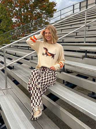 Cream lightweight long sleeved sweater with Weiner Dog graphic on front with orange stripes at the sleeves.