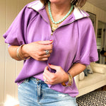 Soft, orchid 1/4 zip top with short sleeves and white striped trim at the collar and elastic sleeves. Loose hem.
