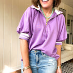 Soft, orchid 1/4 zip top with short sleeves and white striped trim at the collar and elastic sleeves. Loose hem.