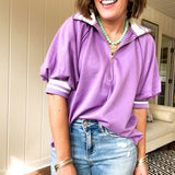 Soft, orchid 1/4 zip top with short sleeves and white striped trim at the collar and elastic sleeves. Loose hem.