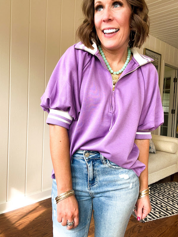 Soft, orchid 1/4 zip top with short sleeves and white striped trim at the collar and elastic sleeves. Loose hem.