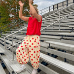 Soft, stretchy cream elastic drawstring waist pants with large red polka dots throughout, pockets and button cuffs for a balloon-like silhouette.