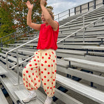Soft, stretchy cream elastic drawstring waist pants with large red polka dots throughout, pockets and button cuffs for a balloon-like silhouette.
