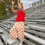 Soft, stretchy cream elastic drawstring waist pants with large red polka dots throughout, pockets and button cuffs for a balloon-like silhouette.