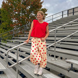 Soft, stretchy cream elastic drawstring waist pants with large red polka dots throughout, pockets and button cuffs for a balloon-like silhouette.