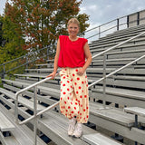 Soft, stretchy cream elastic drawstring waist pants with large red polka dots throughout, pockets and button cuffs for a balloon-like silhouette.