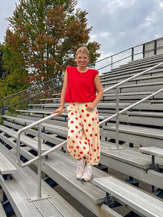 Soft, stretchy cream elastic drawstring waist pants with large red polka dots throughout, pockets and button cuffs for a balloon-like silhouette.