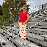 Soft, stretchy cream elastic drawstring waist pants with large red polka dots throughout, pockets and button cuffs for a balloon-like silhouette.