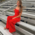 Red jumpsuit with white polka dots throughout, adjustable, removable spaghetti straps, wide leg design and cutout at the back.