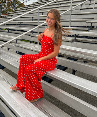 Red jumpsuit with white polka dots throughout, adjustable, removable spaghetti straps, wide leg design and cutout at the back.