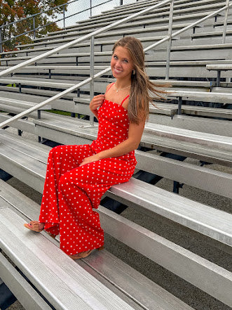 Red jumpsuit with white polka dots throughout, adjustable, removable spaghetti straps, wide leg design and cutout at the back.