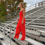 Red jumpsuit with white polka dots throughout, adjustable, removable spaghetti straps, wide leg design and cutout at the back.