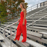 Red jumpsuit with white polka dots throughout, adjustable, removable spaghetti straps, wide leg design and cutout at the back.