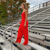 Red jumpsuit with white polka dots throughout, adjustable, removable spaghetti straps, wide leg design and cutout at the back.