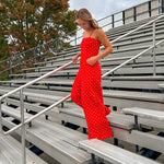 Red jumpsuit with white polka dots throughout, adjustable, removable spaghetti straps, wide leg design and cutout at the back.