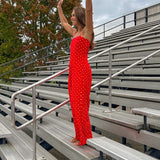 Red jumpsuit with white polka dots throughout, adjustable, removable spaghetti straps, wide leg design and cutout at the back.