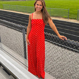 Red jumpsuit with white polka dots throughout, adjustable, removable spaghetti straps, wide leg design and cutout at the back.