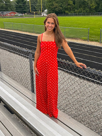 Red jumpsuit with white polka dots throughout, adjustable, removable spaghetti straps, wide leg design and cutout at the back.