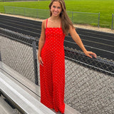 Red jumpsuit with white polka dots throughout, adjustable, removable spaghetti straps, wide leg design and cutout at the back.