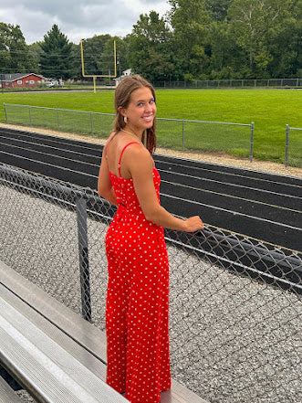 Red jumpsuit with white polka dots throughout, adjustable, removable spaghetti straps, wide leg design and cutout at the back.