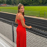 Red jumpsuit with white polka dots throughout, adjustable, removable spaghetti straps, wide leg design and cutout at the back.