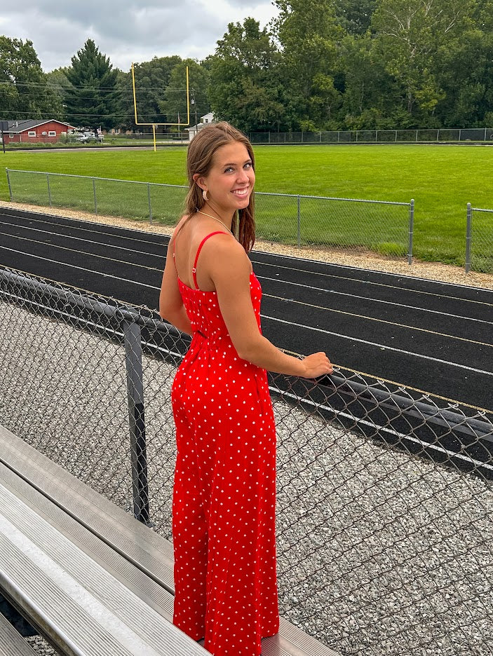 Red jumpsuit with white polka dots throughout, adjustable, removable spaghetti straps, wide leg design and cutout at the back.