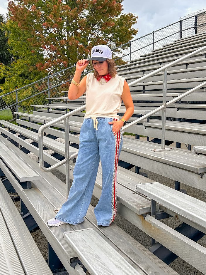 Light wash denim-like wide leg pants with leo and red striping down the sides and elastic, drawstring waist.