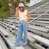 Light wash denim-like wide leg pants with leo and red striping down the sides and elastic, drawstring waist.
