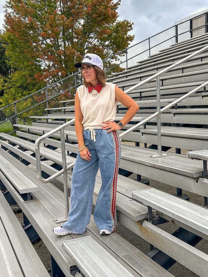 Light wash denim-like wide leg pants with leo and red striping down the sides and elastic, drawstring waist.