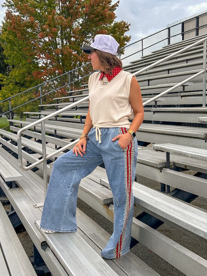 Light wash denim-like wide leg pants with leo and red striping down the sides and elastic, drawstring waist.