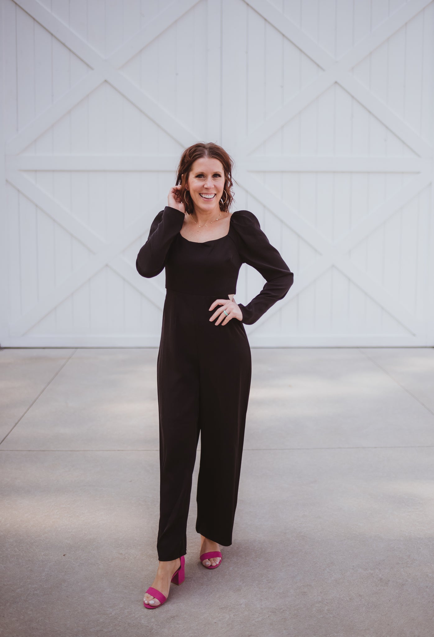 Black silky jumpsuit with puffed long sleeves, square neckline, side cutouts, elastic at the back waist and a tie at the back neckline.
