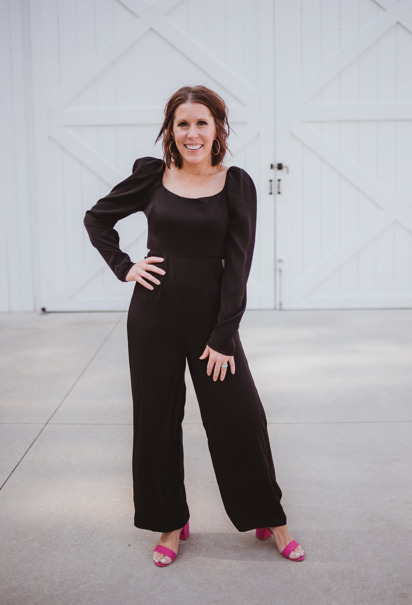 Black silky jumpsuit with puffed long sleeves, square neckline, side cutouts, elastic at the back waist and a tie at the back neckline.